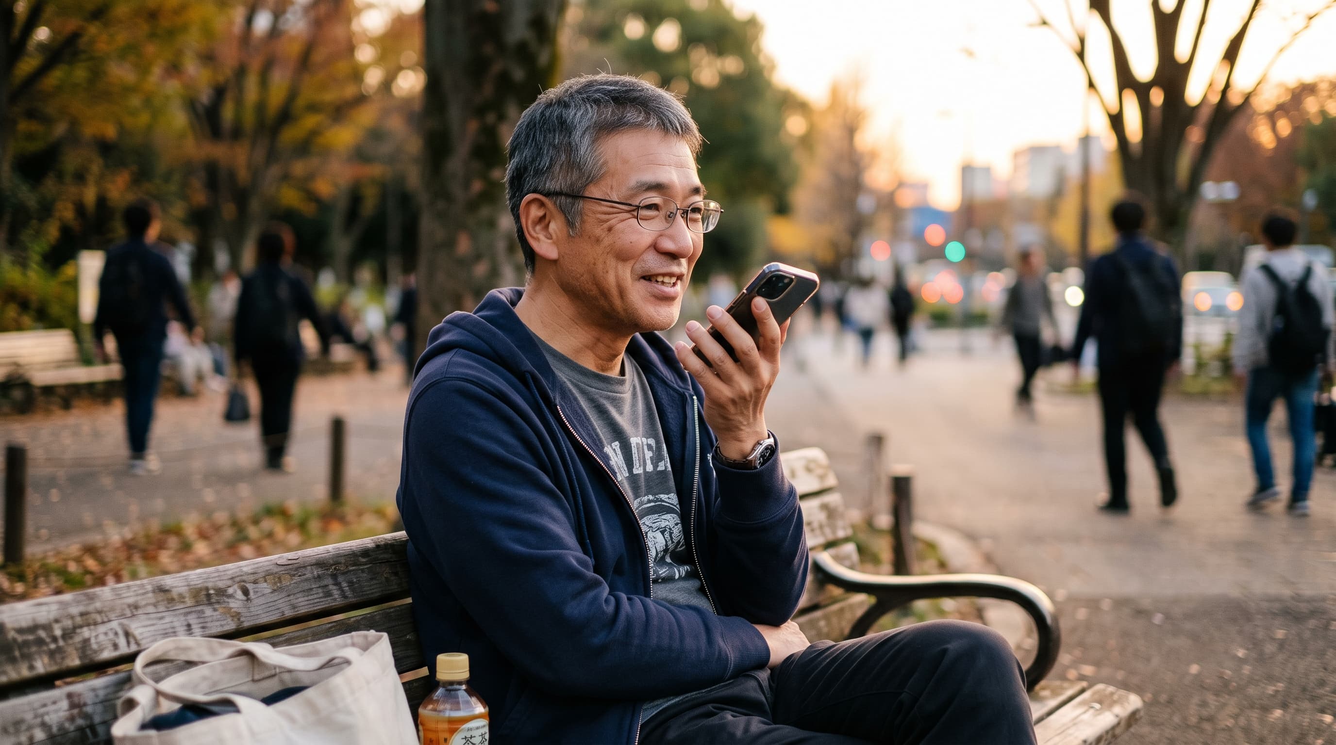 夕方の公園でスマートフォンに話しかける50代の男性