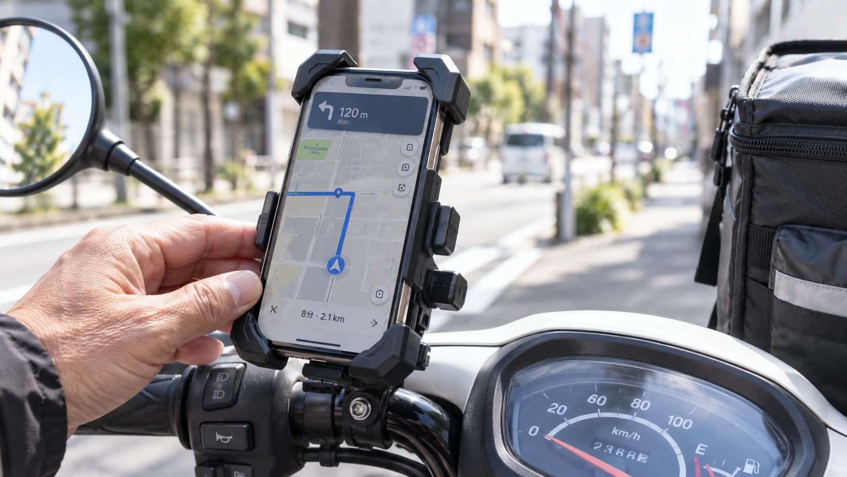 原付のハンドルに取り付けたカエディアのバイク用スマホホルダーと、ナビ画面を操作する配達員の手